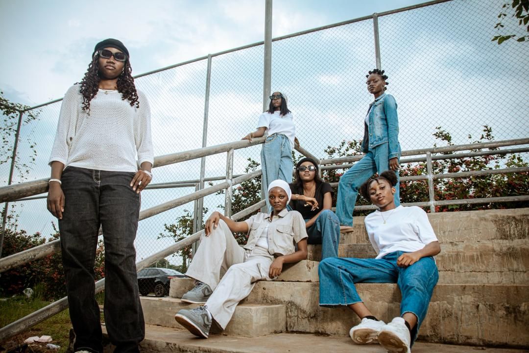 Six creatives posed across concrete steps during a T21 shoot, photographed from a low angle